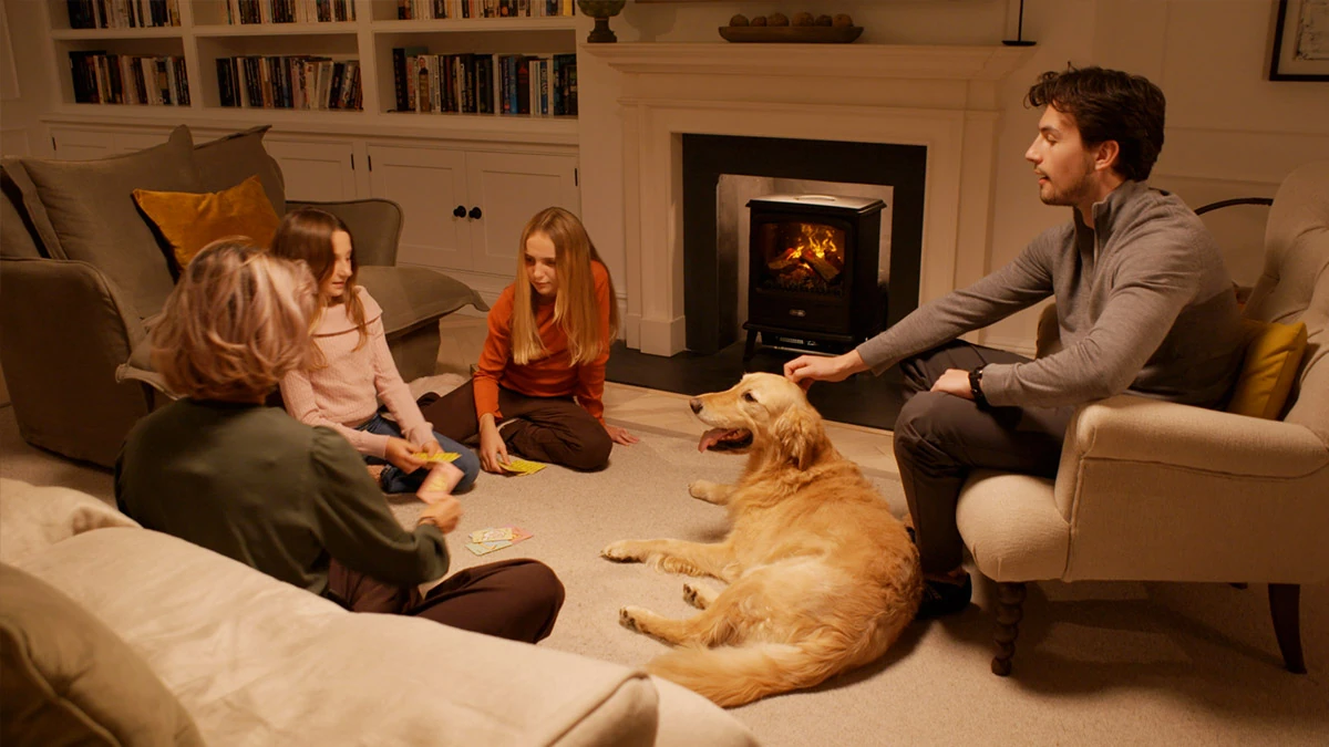 Family relaxing beside a glowing Dimplex Optimyst electric fire