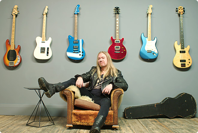 Musician relaxes in leather seating surrounded by his collection of guitars displayed on the wall