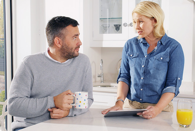 A couple talking about mortgage claims in modern white kitchen