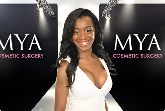 A lady posing on a catwalk with MYA Cosmetic Surgery branding and spotlights illuminating the stage
