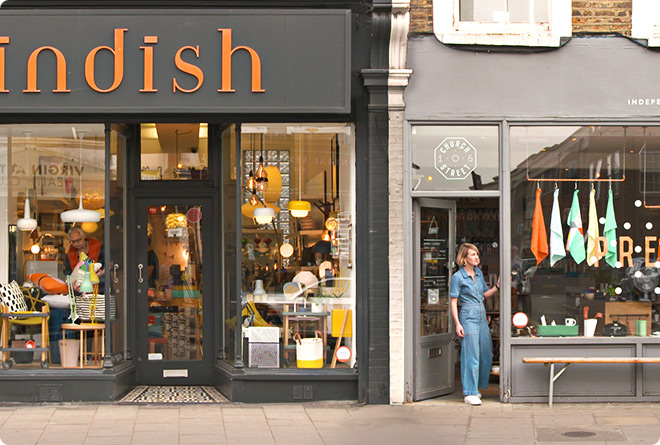 A shopkeeper stood in her boutique's doorway, looking down the high street.